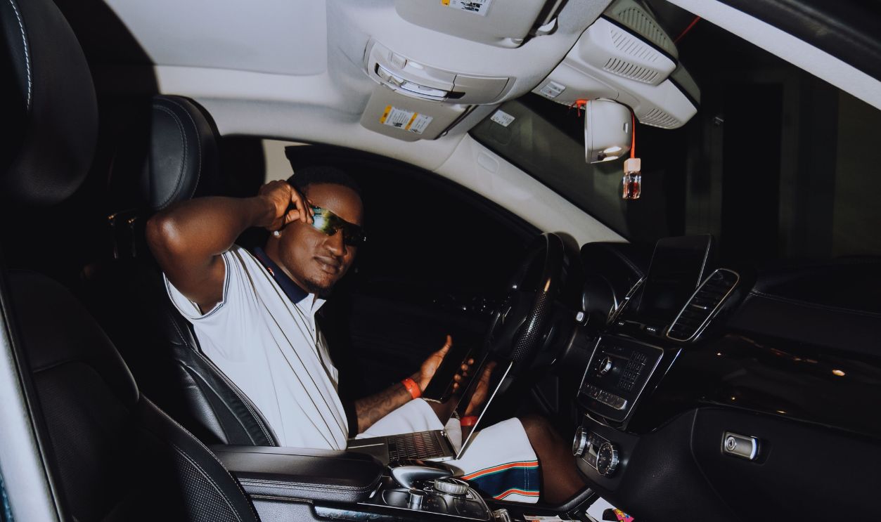 Man wearing sunglasses sitting in a car at night, captured indoors with a cool mood