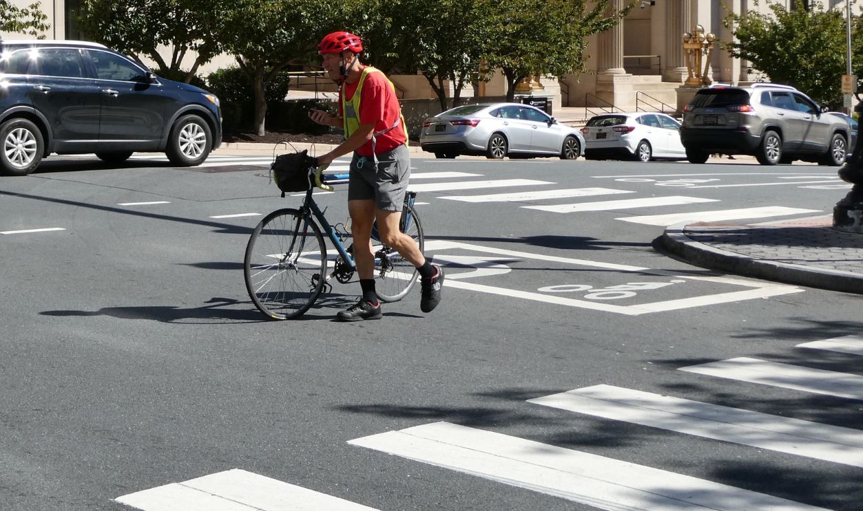 "Wilmington, DelawareUnited States-October 5, 2022: man walking his bike across the street in Wilmington Delaware"