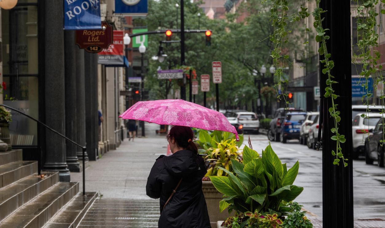 Newport, Rhode Island, USA - January 1, 2024: Girl back view with umbrella walking in rain in streets of Rhode Island