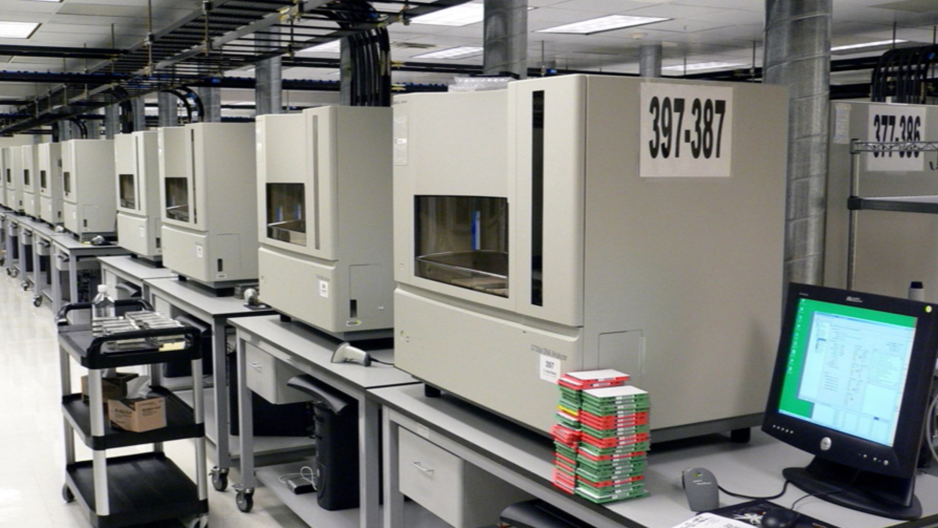A row of DNA sequencing machines on SteelSentry tables (3730xl DNA Analyzer machines from Applied Biosystems).
