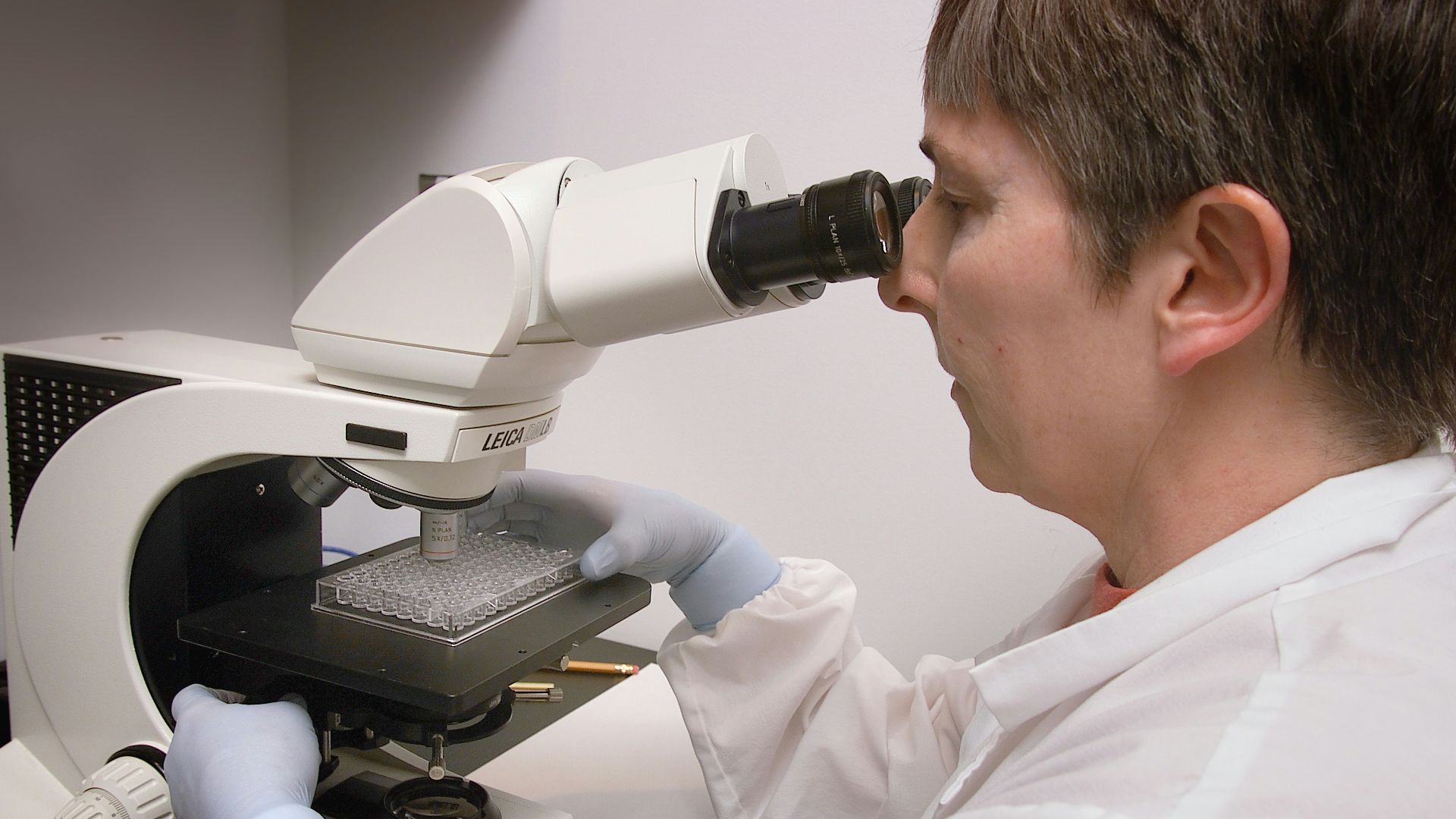 a man in a lab coat looking through a microscope
