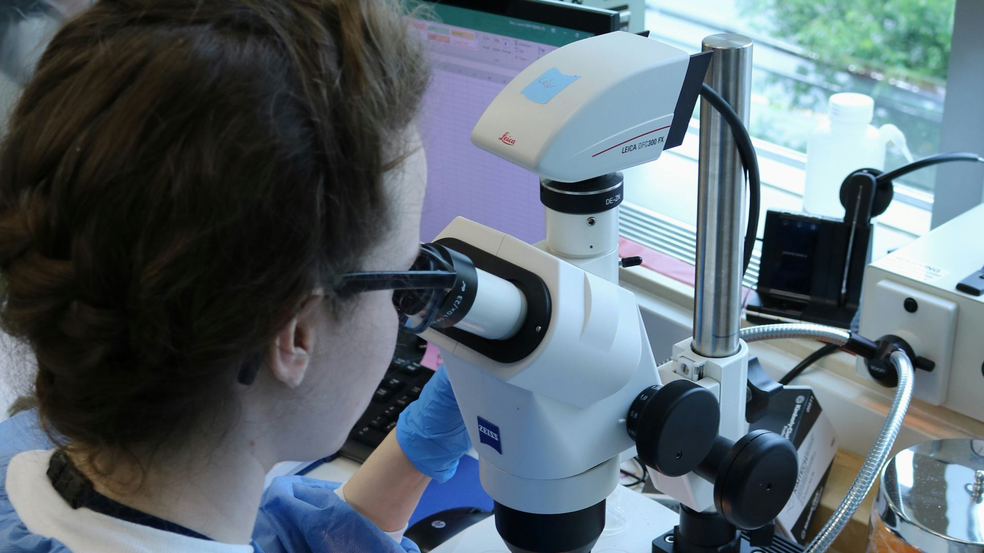 a woman in a lab looking through a microscope