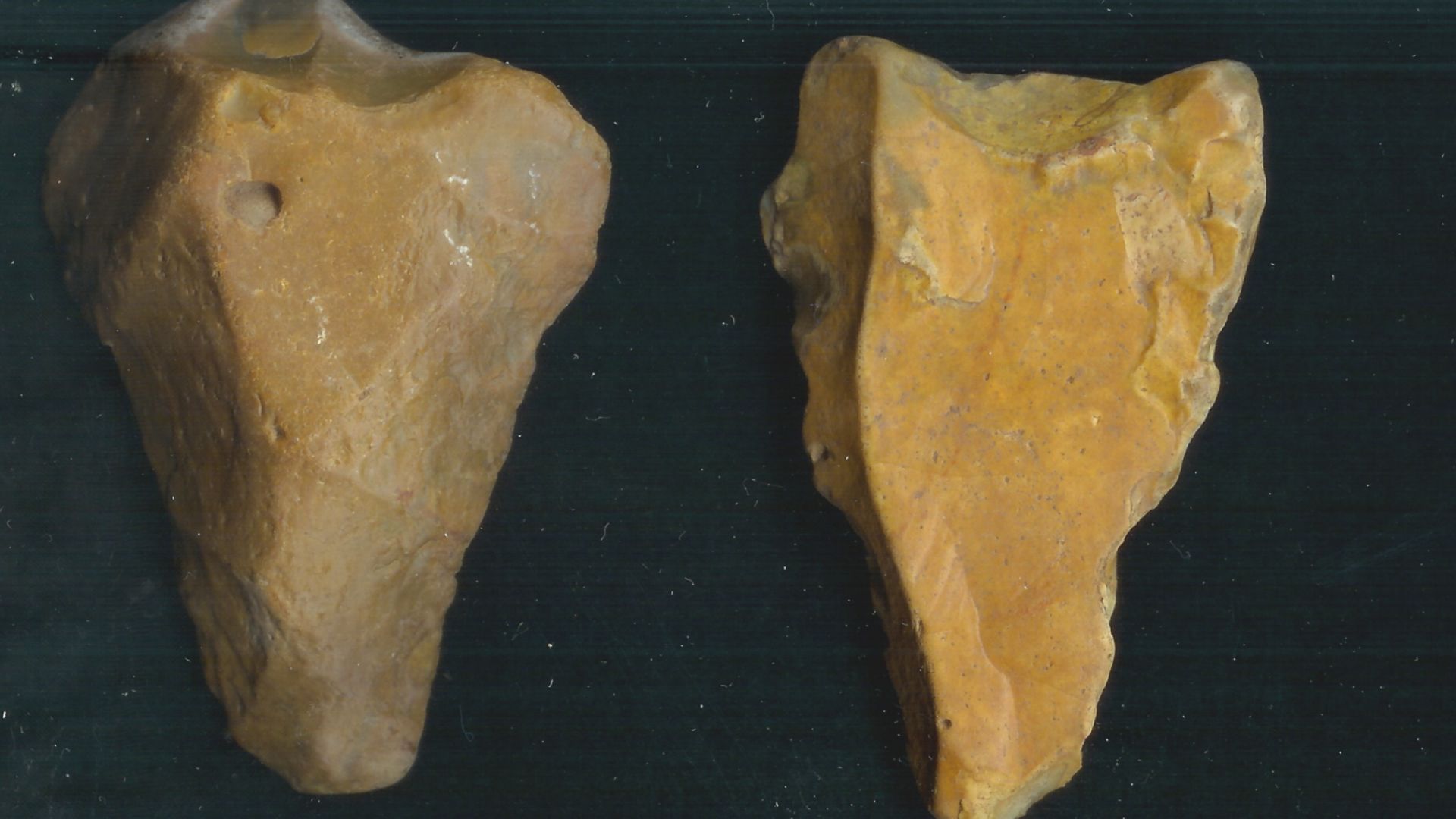 Lithic implements. 
    1. Acheulian hand axe: Flaking scars on both the ventral and dorsal sides around the edge, the tool is triangular in plan with a central point at the bottom, the butt is flat. The flaking scars are large a crude and flint has been 