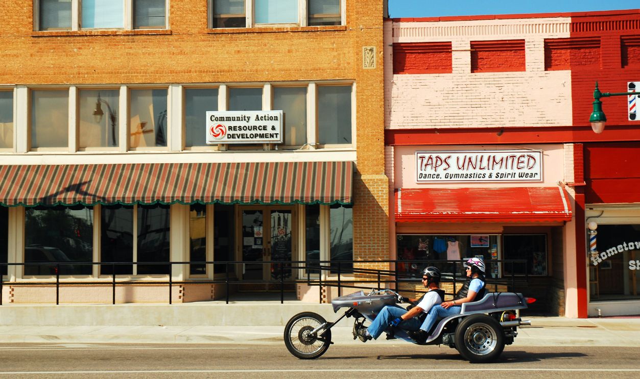 Claremore OK USA May 25 An adult man rides a three wheeled motorcycle through the small town downtown district of Claremore Oklahoma