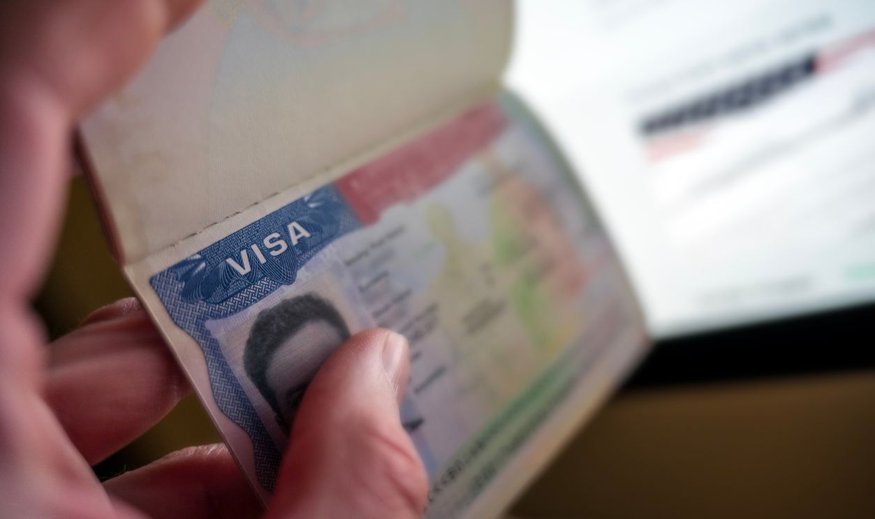 Unknown causian person holding passport with visa issued fot United States of America