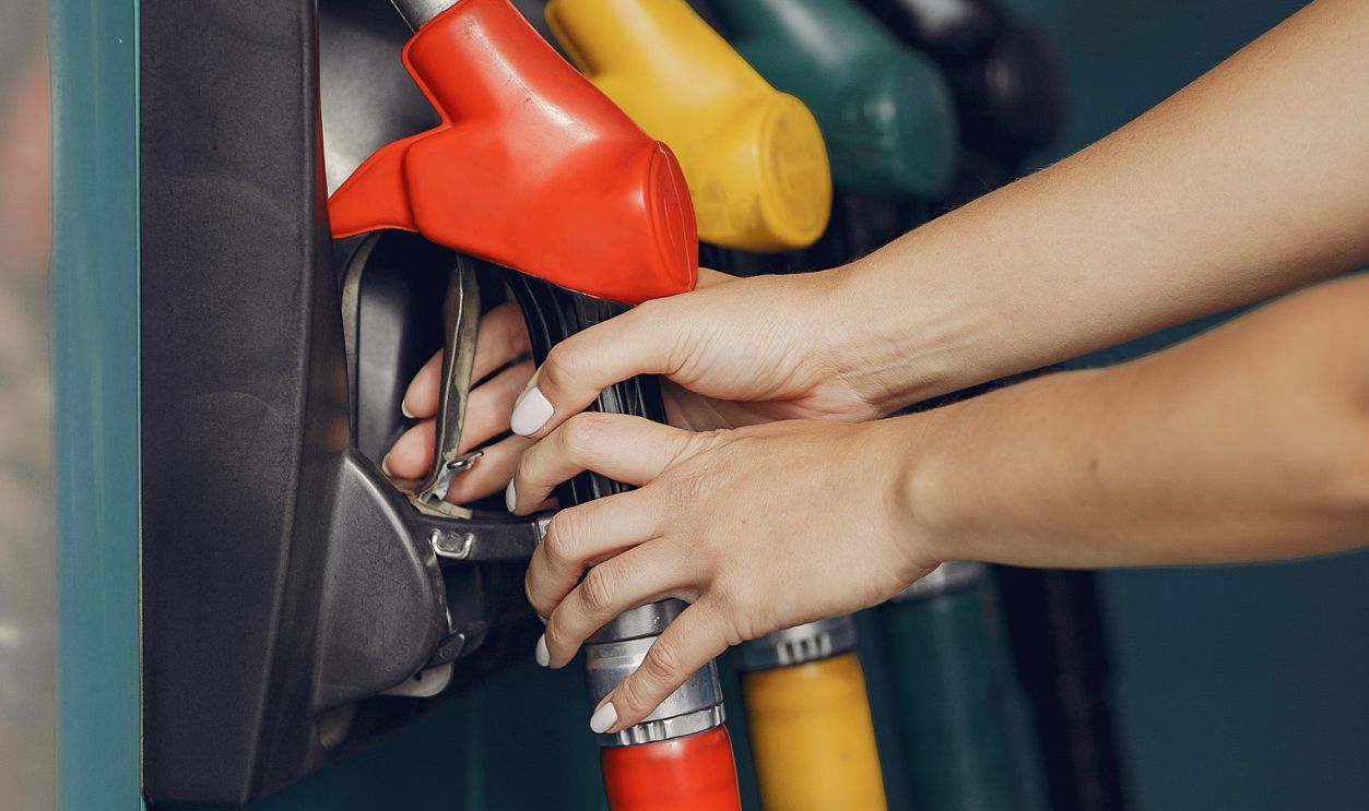 Woman's hands refueling vehicle at gas station with colorful fuel nozzles