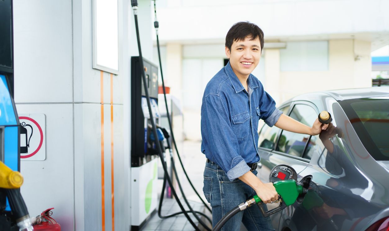 Happy cheerful middle adult man refueling his car at self-service gas station, man refilling his vehicle gas at the gas station.