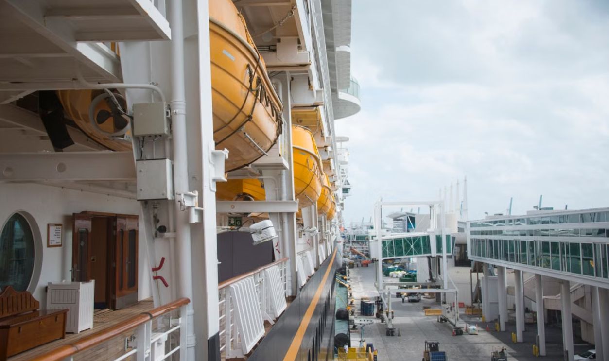 A detailed view of life boats on a docked cruise ship at a port, showcasing maritime safety equipment and infrastructure