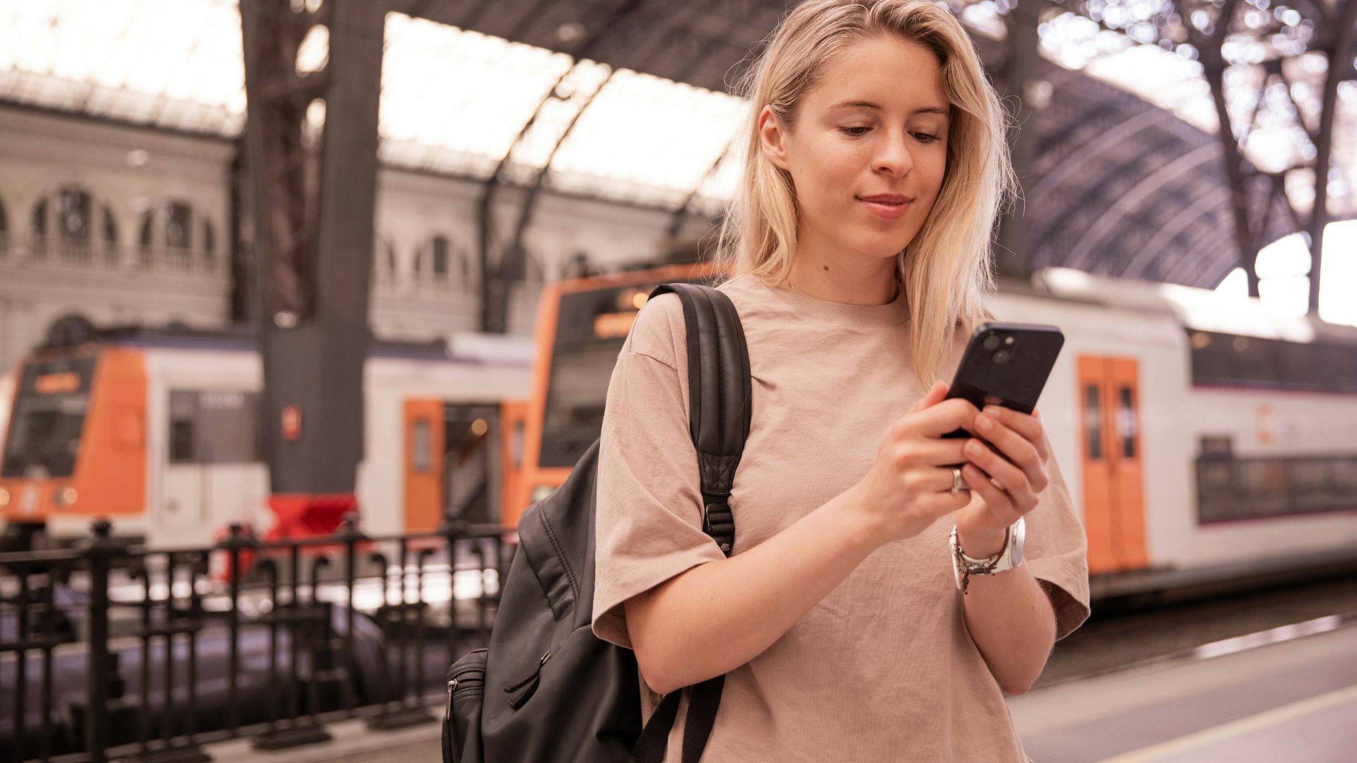 a woman standing in a train station looking at her cell phone