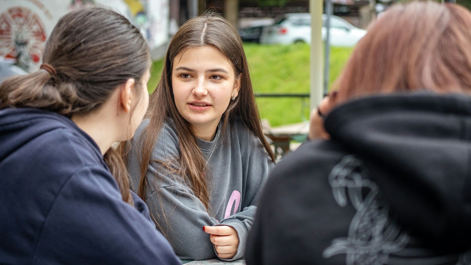Three young women talking at an outdoor table