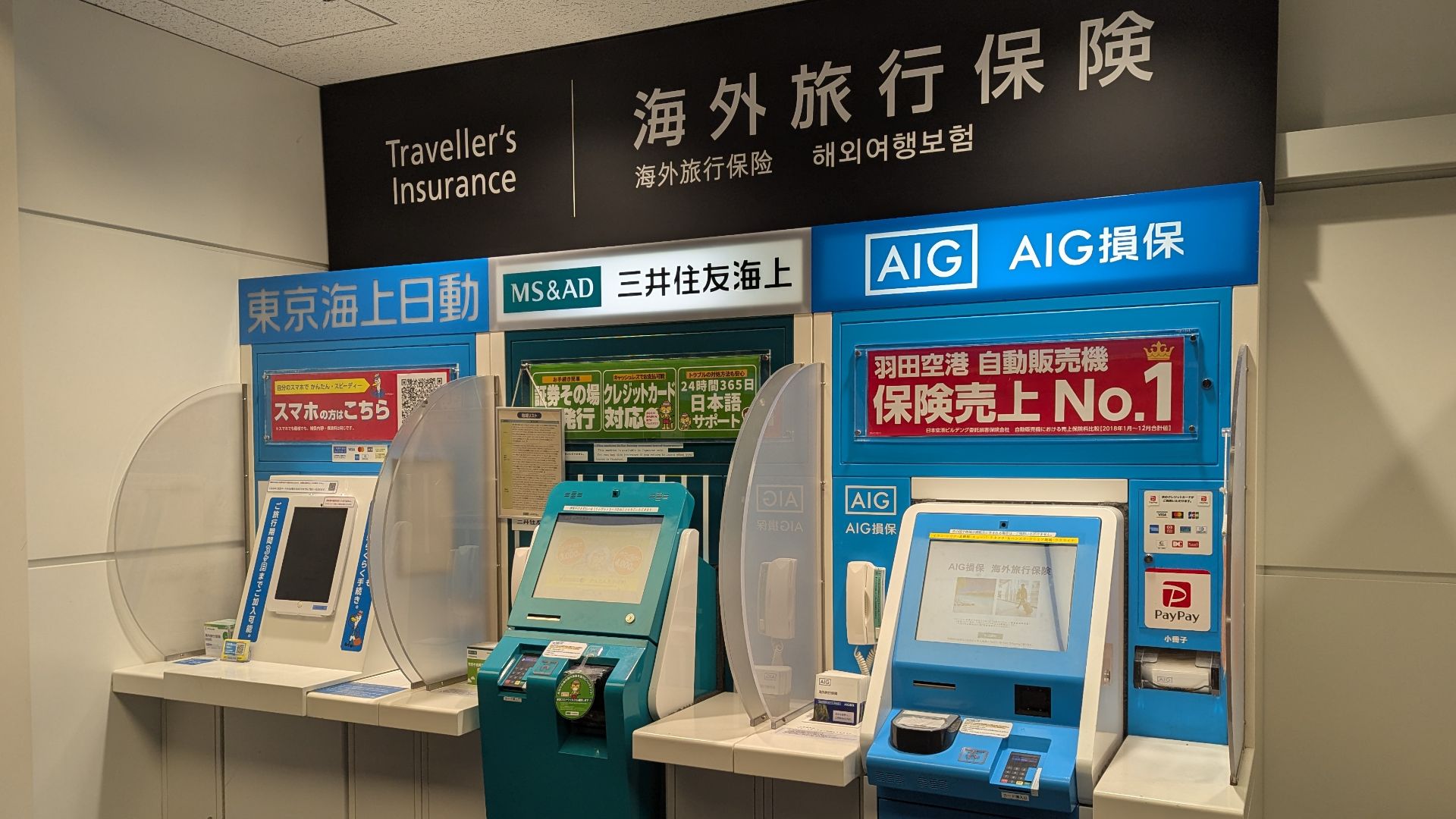 Three vending machines at Haneda Airport Terminal 3 selling travel insurance from different insurance companies, 東京海上日動火災保険, 三井住友海上火災保険, AIG損害保険.