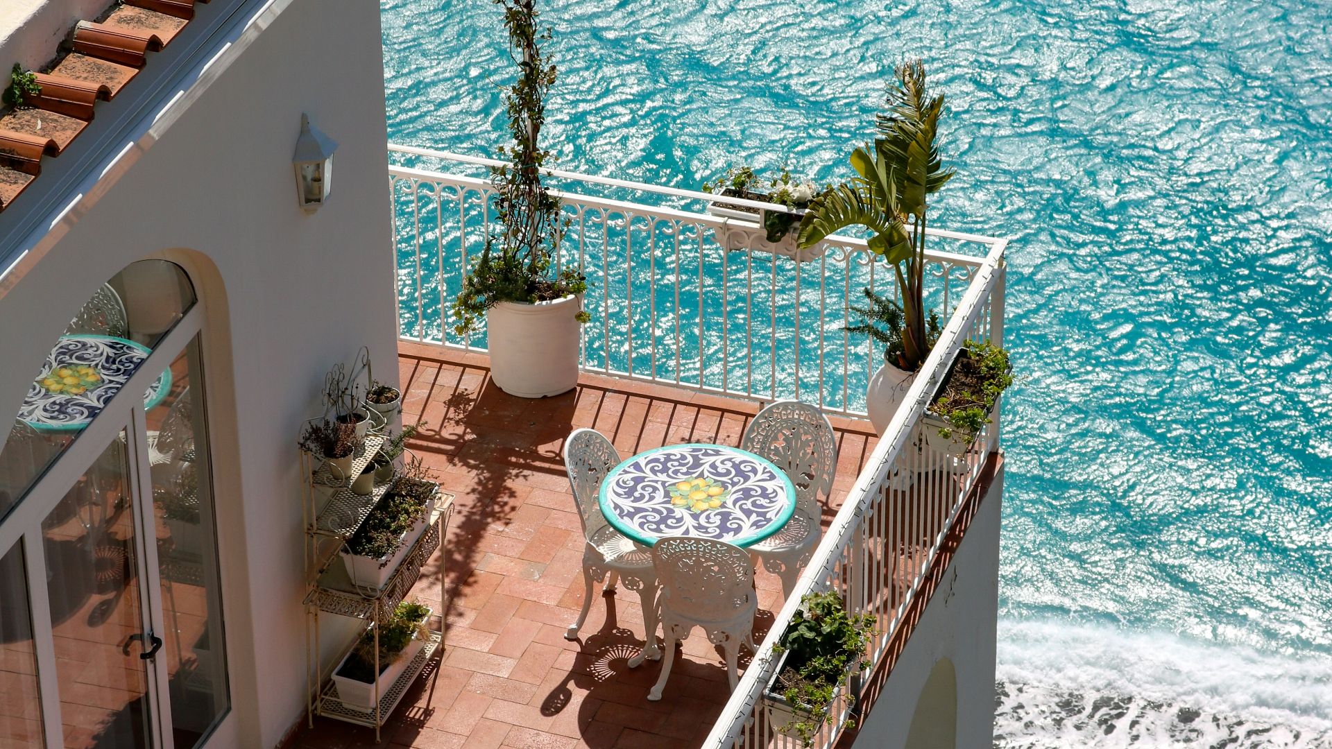 A tiled terrace with a small table and chairs overlooking the blue sea