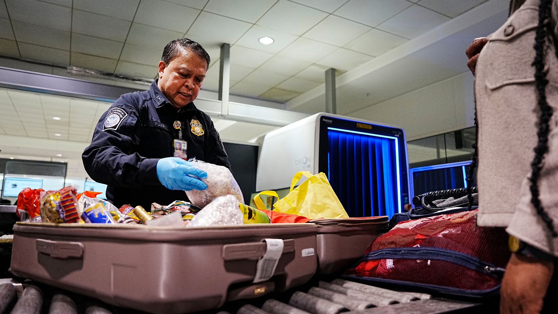 A U.S. Customs and Border Protection Office of Field Operations agriculture specialist searches the luggage of international travelers arriving at Baltimore/Washington International Thurgood Marshall Airport February 27, 2025. CBP Photo by Glenn Fawcett