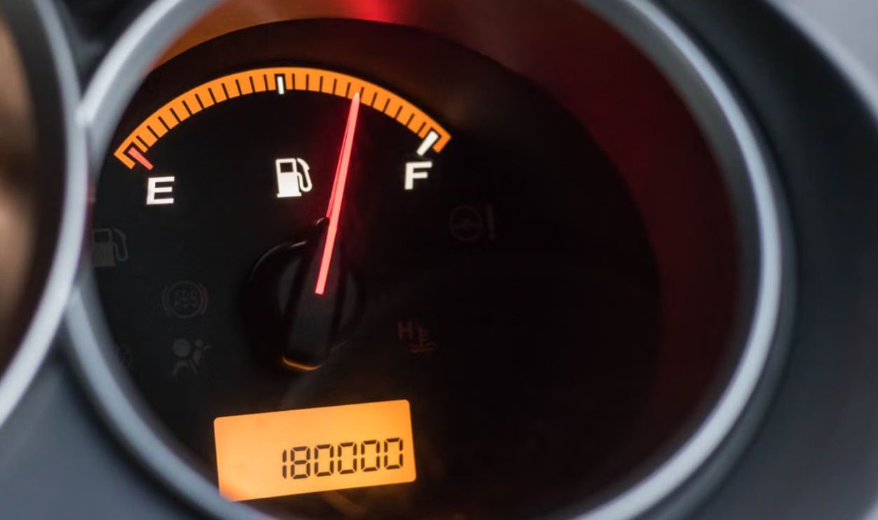 Close-up image of a car's fuel gauge showing a full tank with an odometer reading of 180000 miles