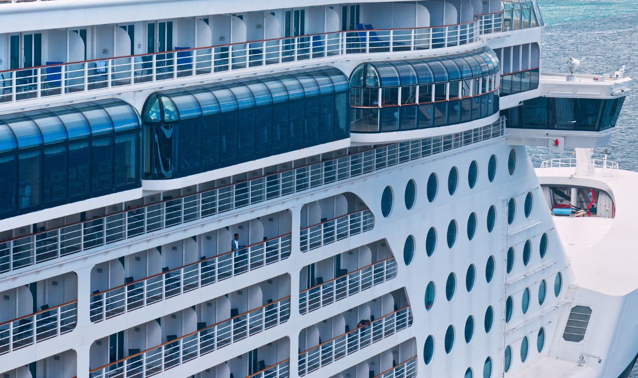 A luxurious cruise ship docked at a tropical port with clear blue skies and calm seas