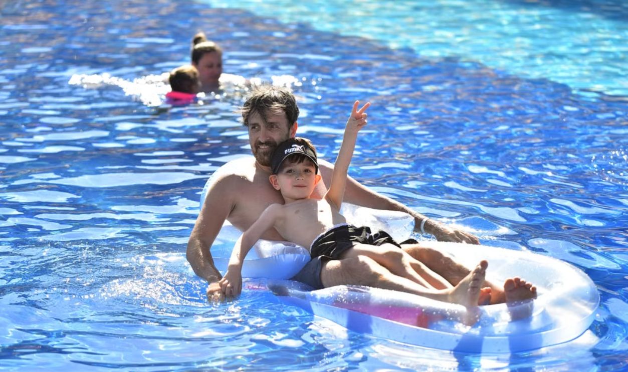 Father and son enjoying summer on an inflatable mattress in a sunny pool.