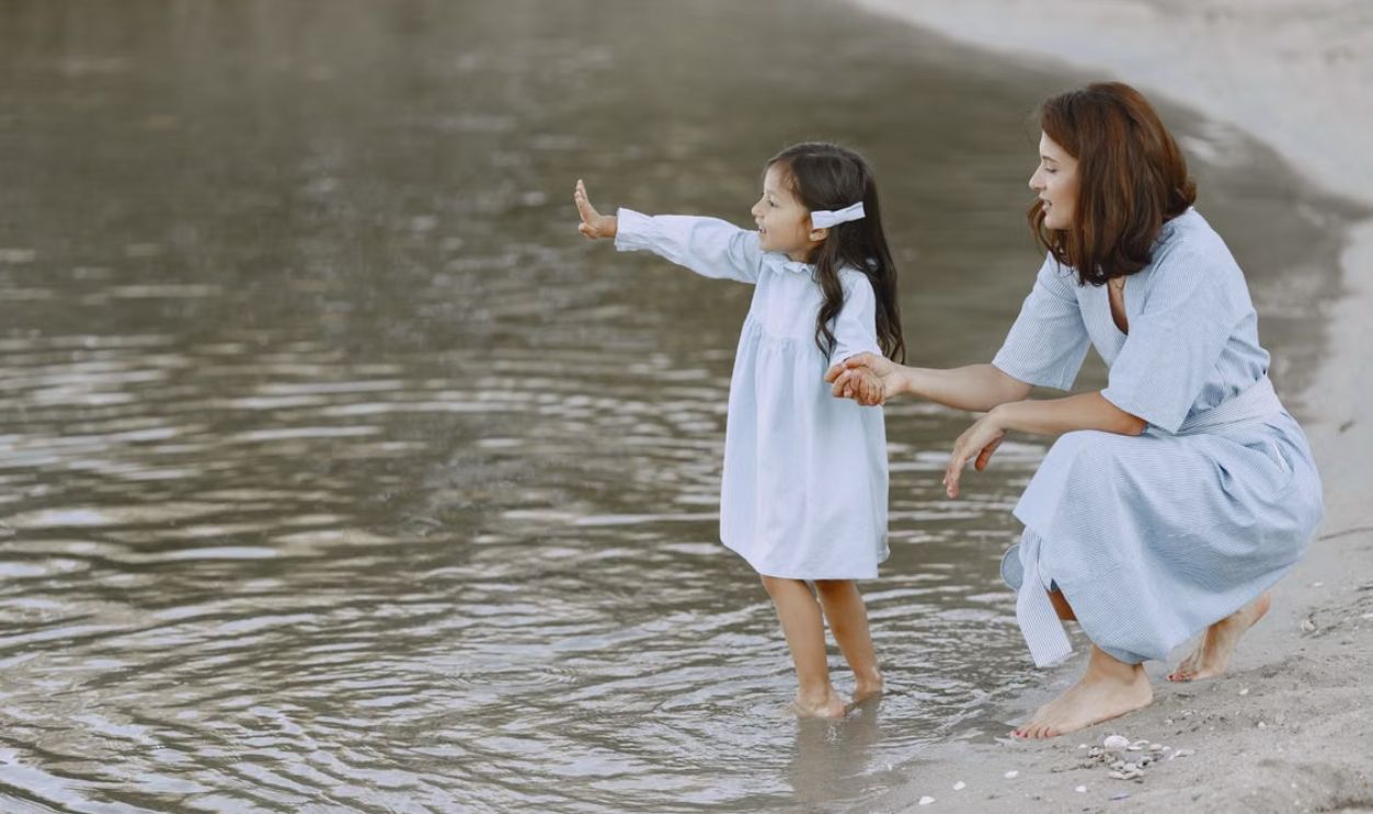 A joyful mother and daughter bonding by a tranquil lake on a sunny day.