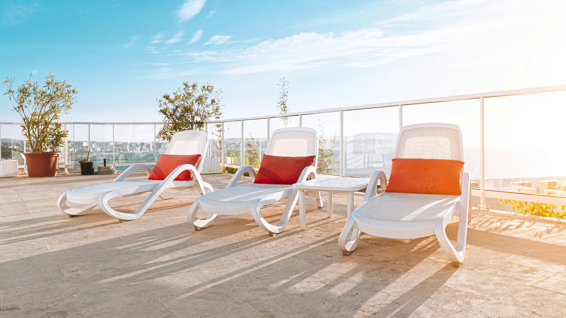 three white lawn chair with orange pillows