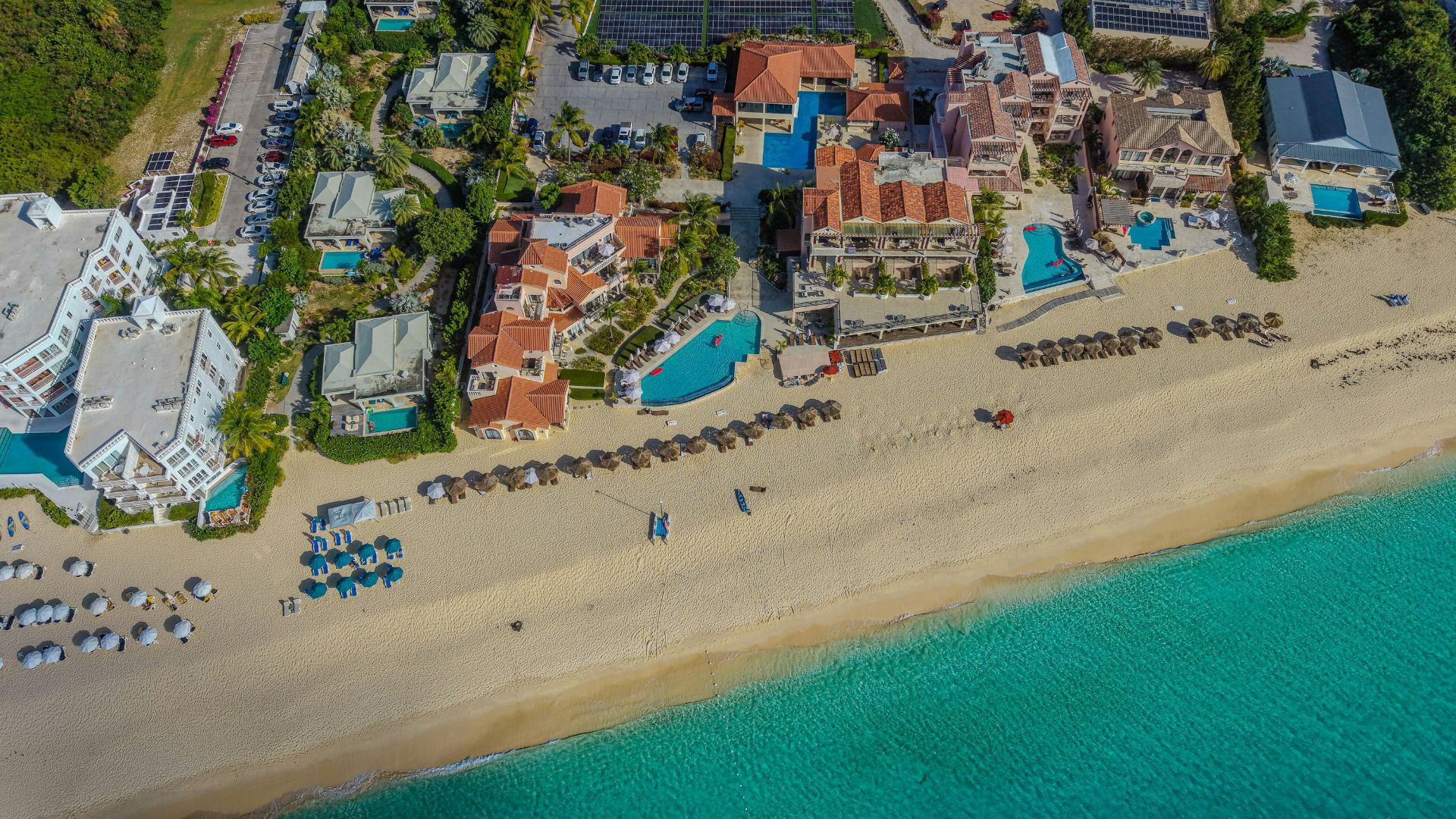 Luxury resorts line a sandy beach with turquoise ocean