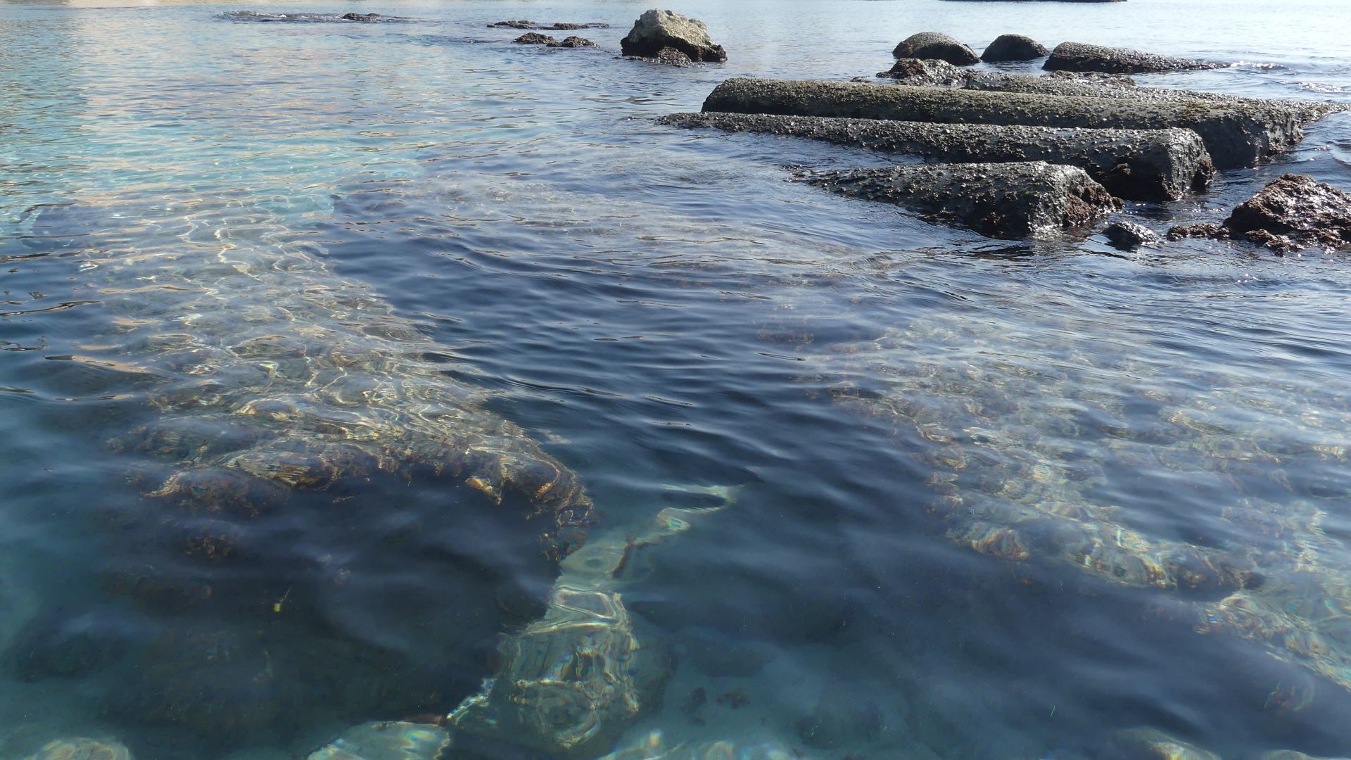 Ancient columns lie in the submerged Egyptian harbour of Tyre/Sour, South Lebanon, with the skyline of the modern city in the background.
