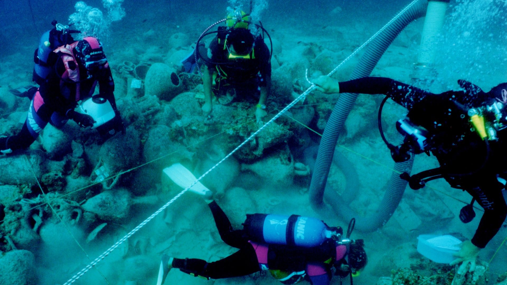 Diving archaeologists excavating the Alonnisos shipwreck in fall 2000, trench Θ3. The 2x2 m rope grid and airlift are visible.
