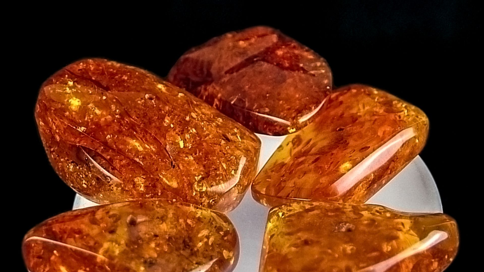 Tumble-polished and drilled Baltic amber. Displayed on an upside-down drinking glass (for size). Studio photography in Vibble, Visby, Gotland, Sweden.