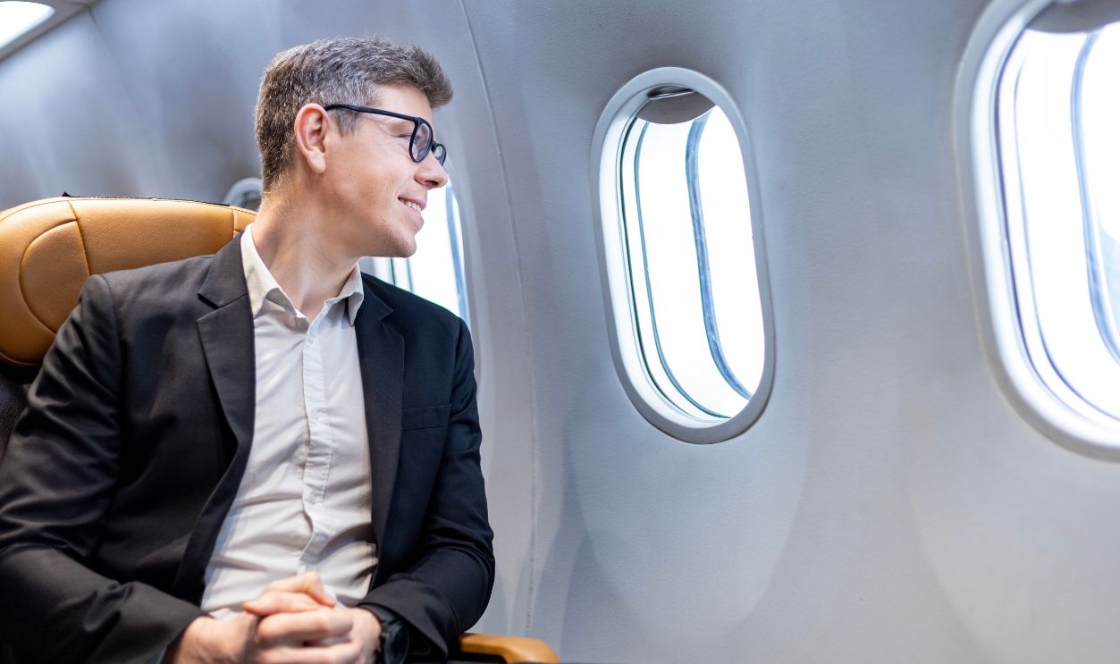 2234787739 : Caucasian businessman is traveling and sitting comfortably in the aircraft while looking out the window for business travel in economy class