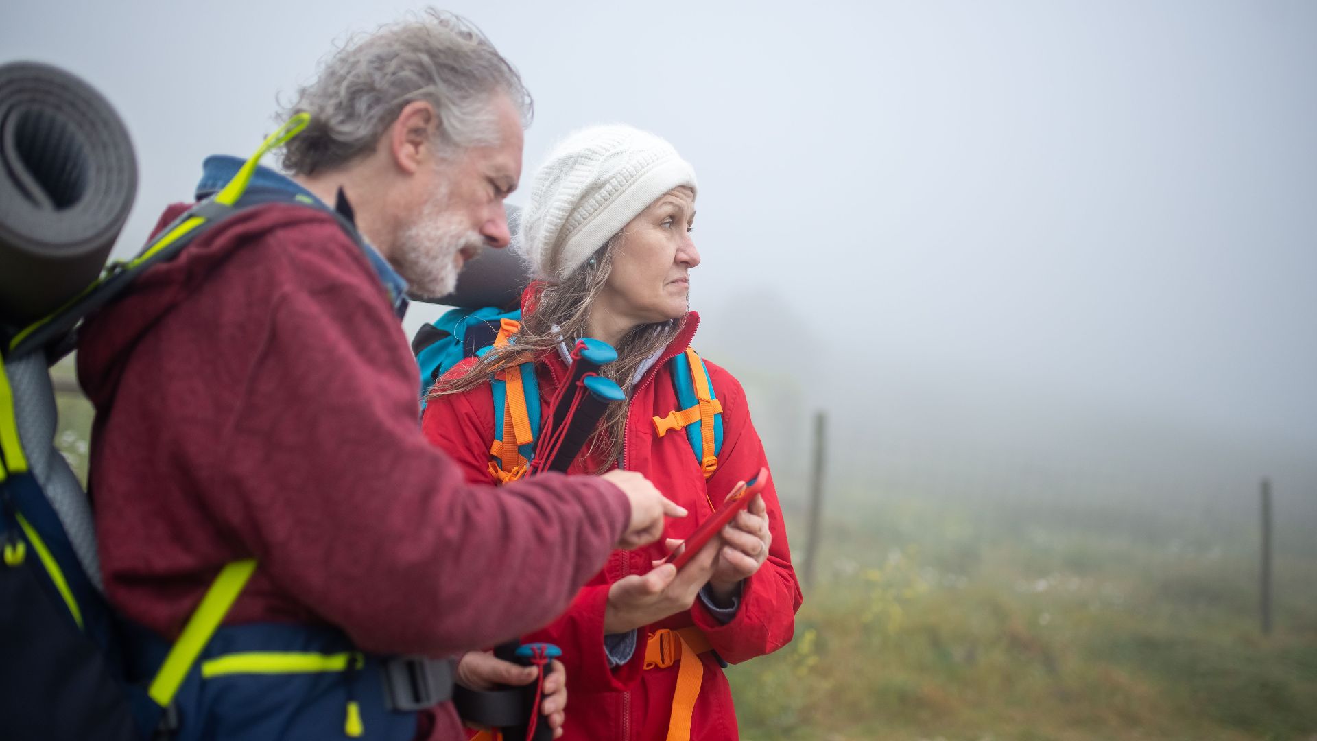 Two hikers consult a smartphone in a foggy rural landscape in Portugal.