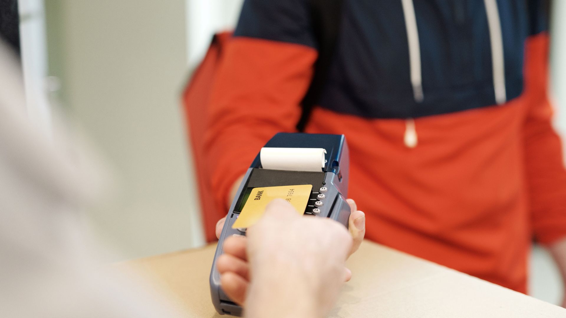 Close-up view of a contactless payment transaction using a credit card on a terminal device.
