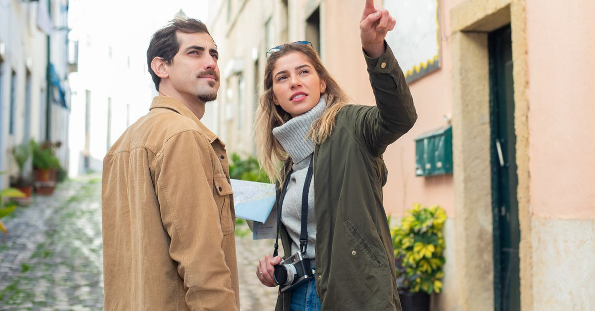 Young couple navigating a European street with a map, showcasing travel adventure.