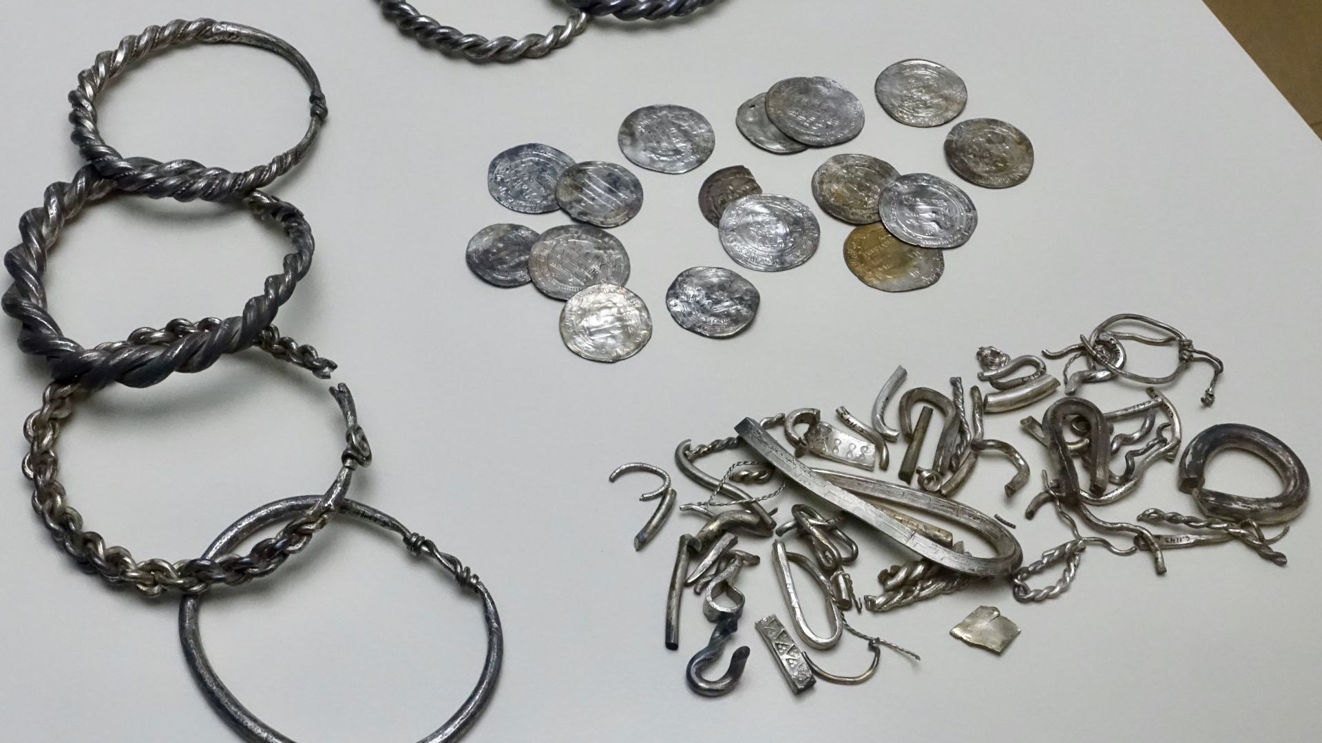 01. Silver hoard (in Norwegian: sølvskatt) found in 1844 at Teisen Farm in Oslo, Norway: seven arm rings (probably made from melted down coins), one ingot, many pieces of hack-silver, 16 whole and many pieces of Arabian and Persian (Kufic) coins. The new