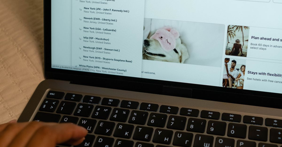 Person typing on laptop, searching flight details indoors, focusing on travel planning and booking.