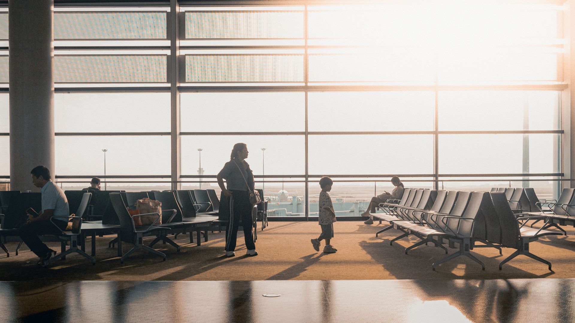Silhouettes of travelers in a sunlit airport terminal in Shanghai, China.