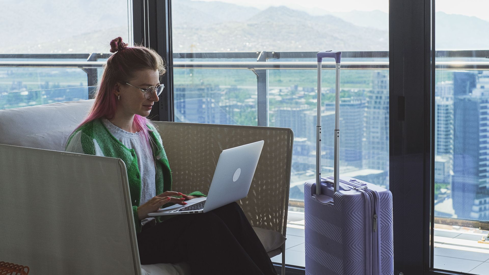 Woman working on a laptop in a hotel lounge with a stunning city view.