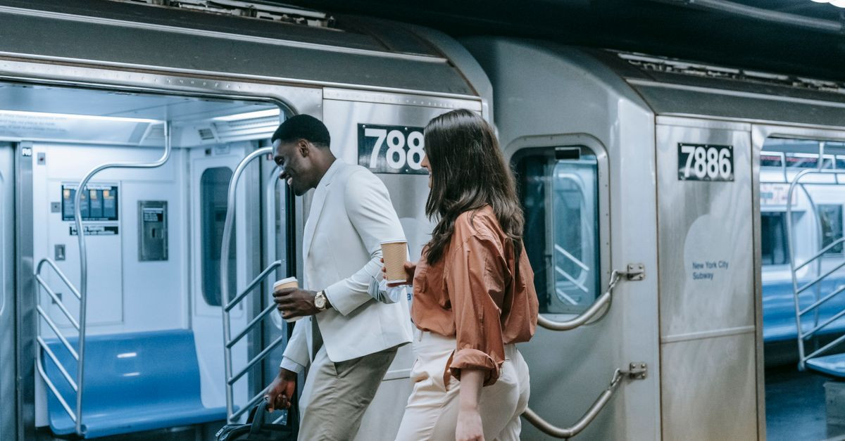 Two colleagues walking on the New York subway platform, engaging in casual conversation.