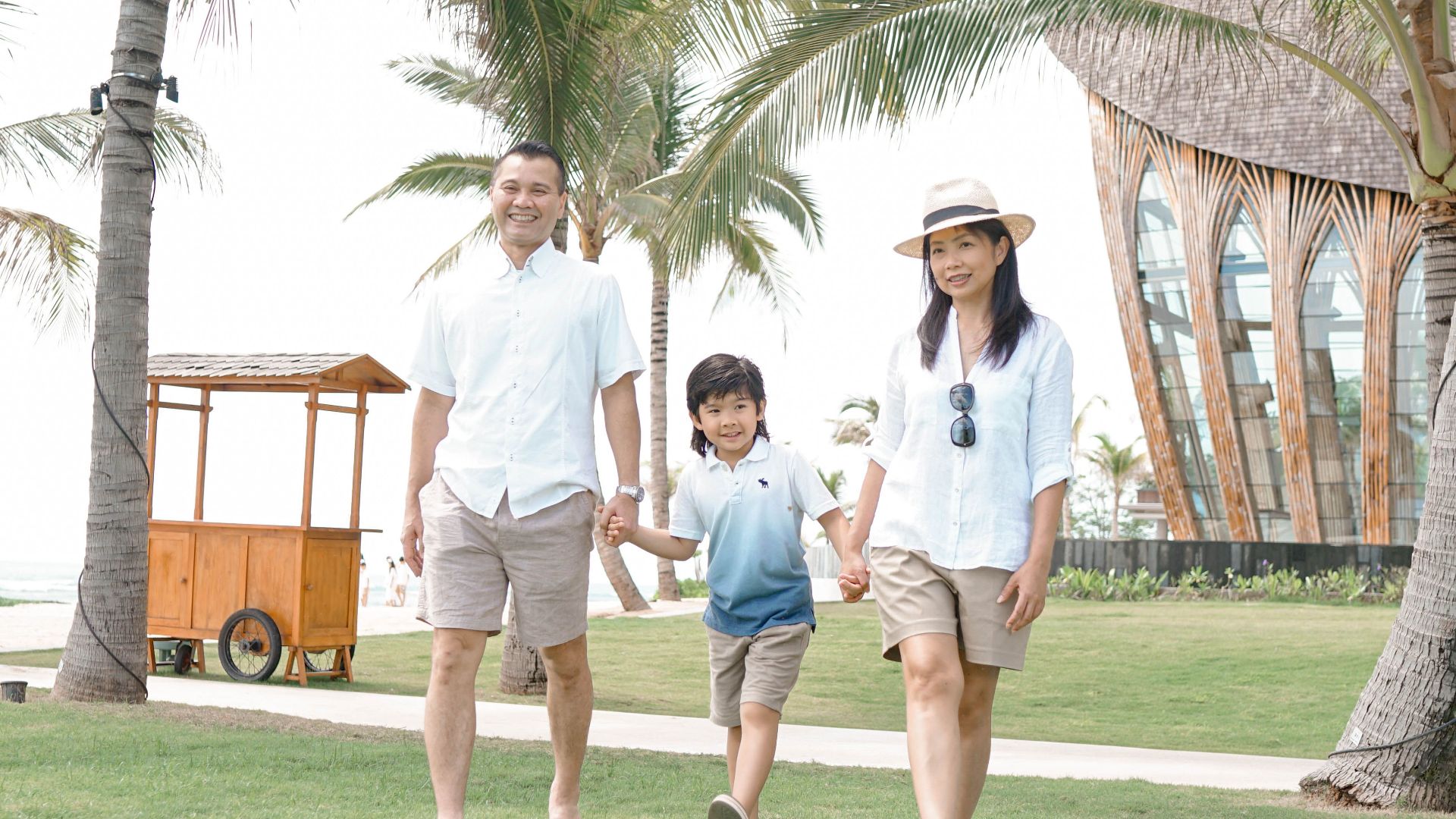 Happy family walking hand in hand through a lush resort in Bali, Indonesia, enjoying a sunny vacation day.