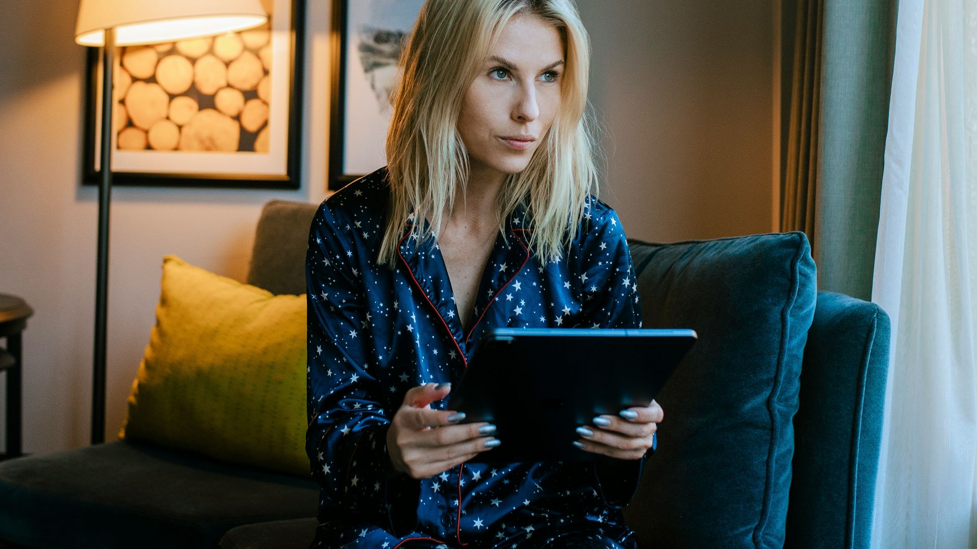 a woman sitting on a couch looking at a tablet