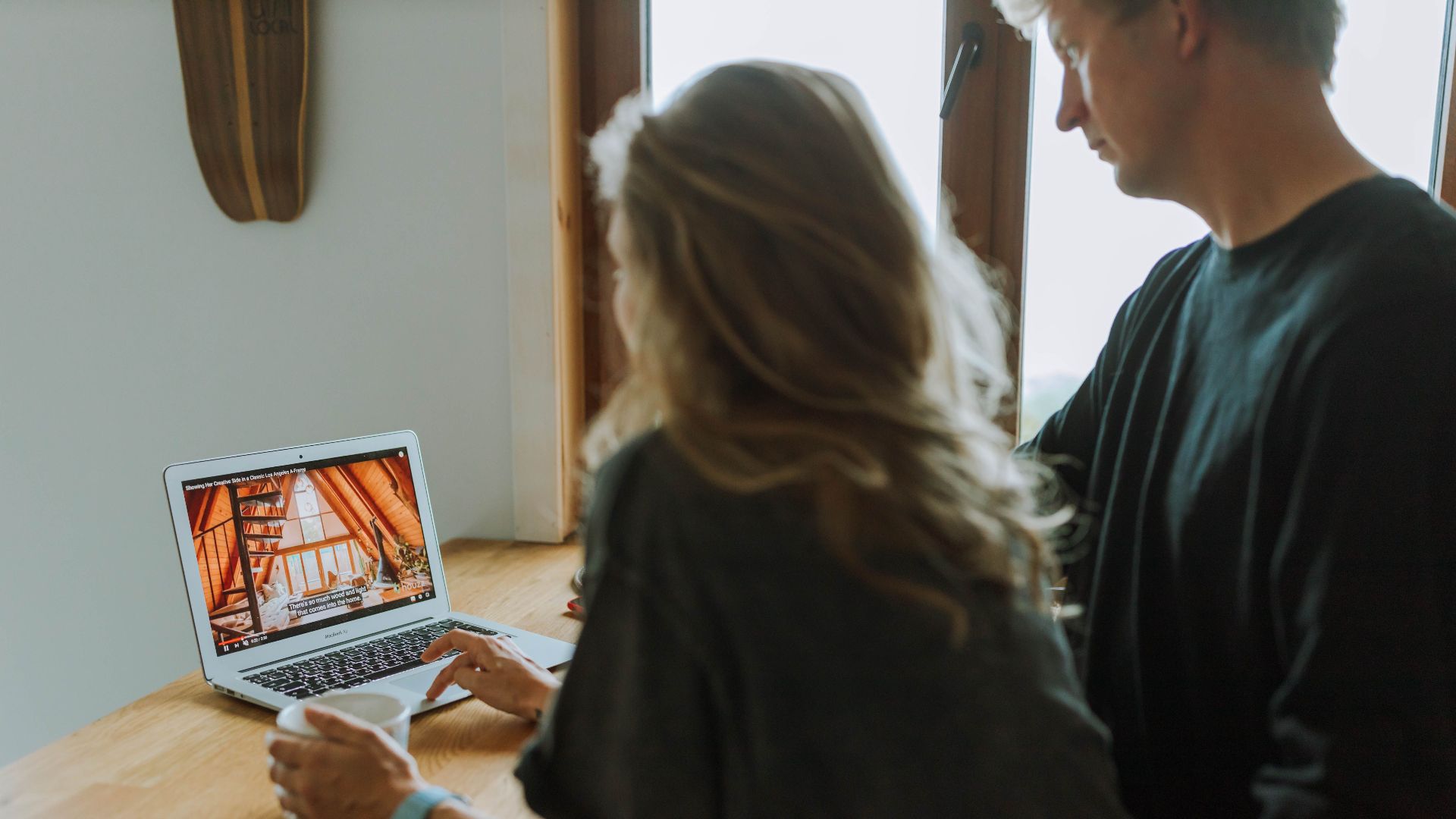 A couple viewing home interior design on a laptop while enjoying coffee together indoors.