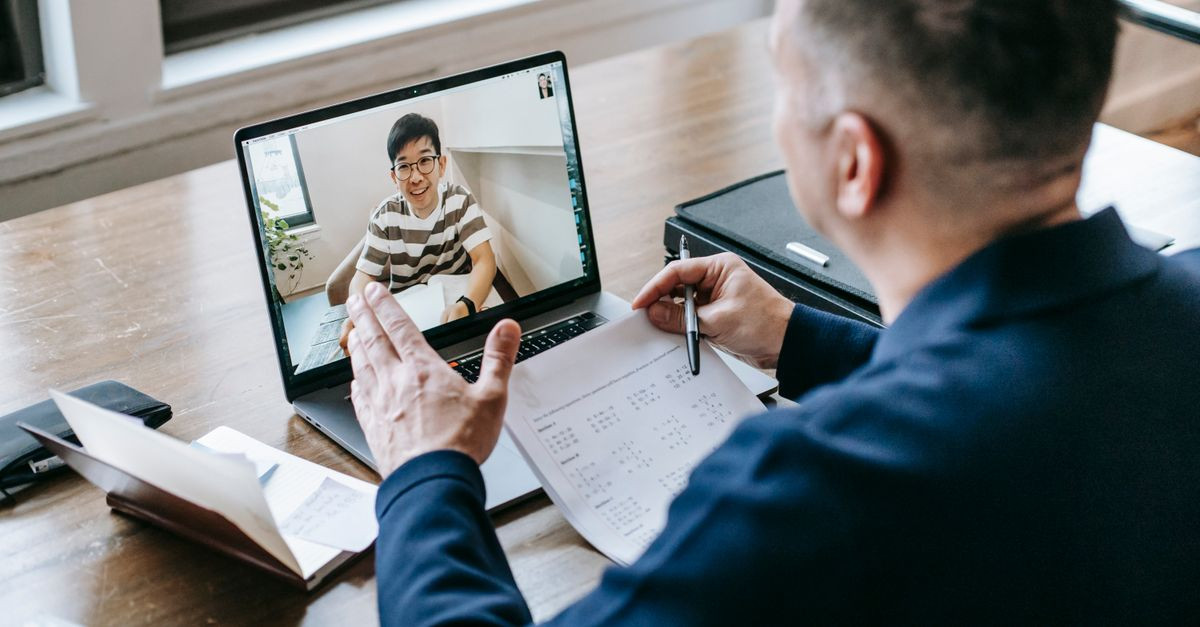 A professional having a video conference on a laptop from a home office, engaging in online communication.
