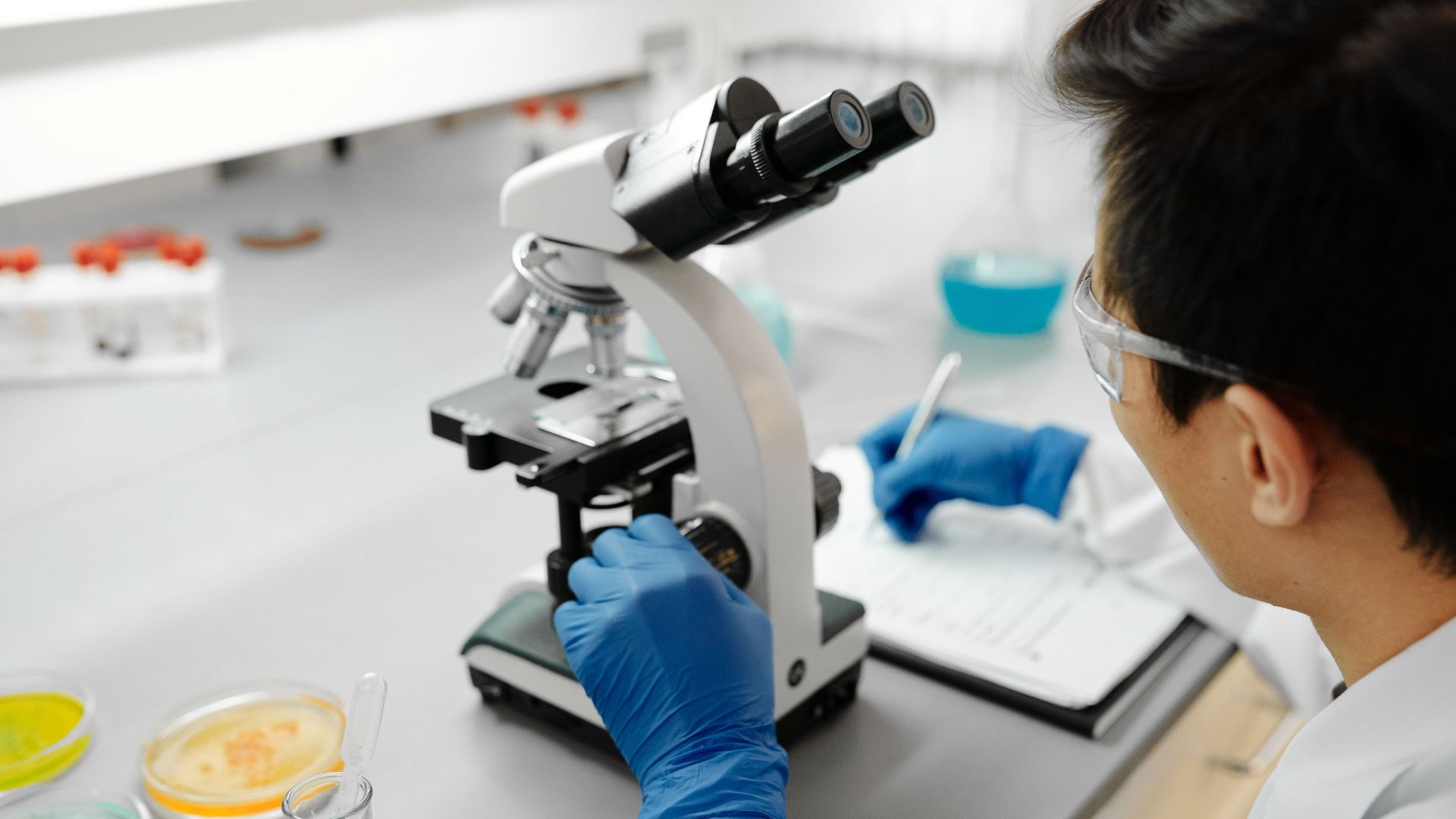Scientist using a microscope to analyze samples in a modern laboratory environment.