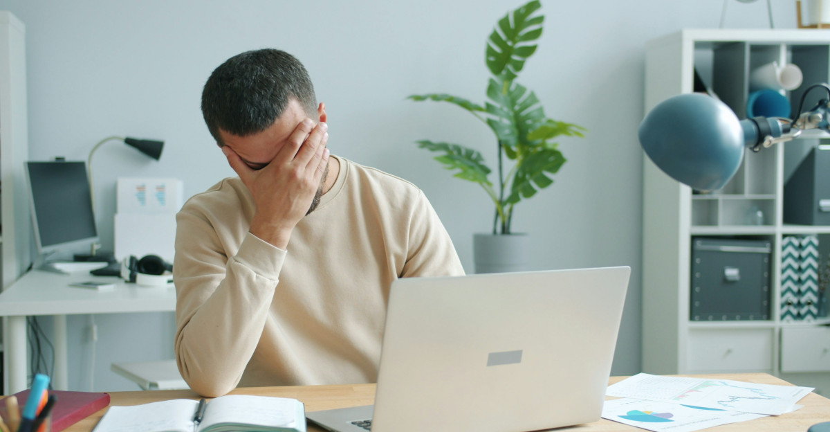Man rubbing his face in front of laptop