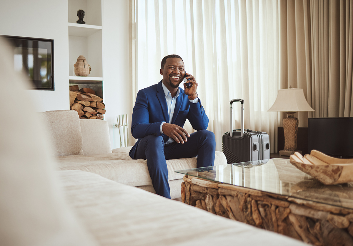  Downloaded Happy businessman in hotel, on smartphone call and business communication for work in Atlanta. Young black entrepreneur, listening to audio on cellphone and sitting on luxury sofa in living room