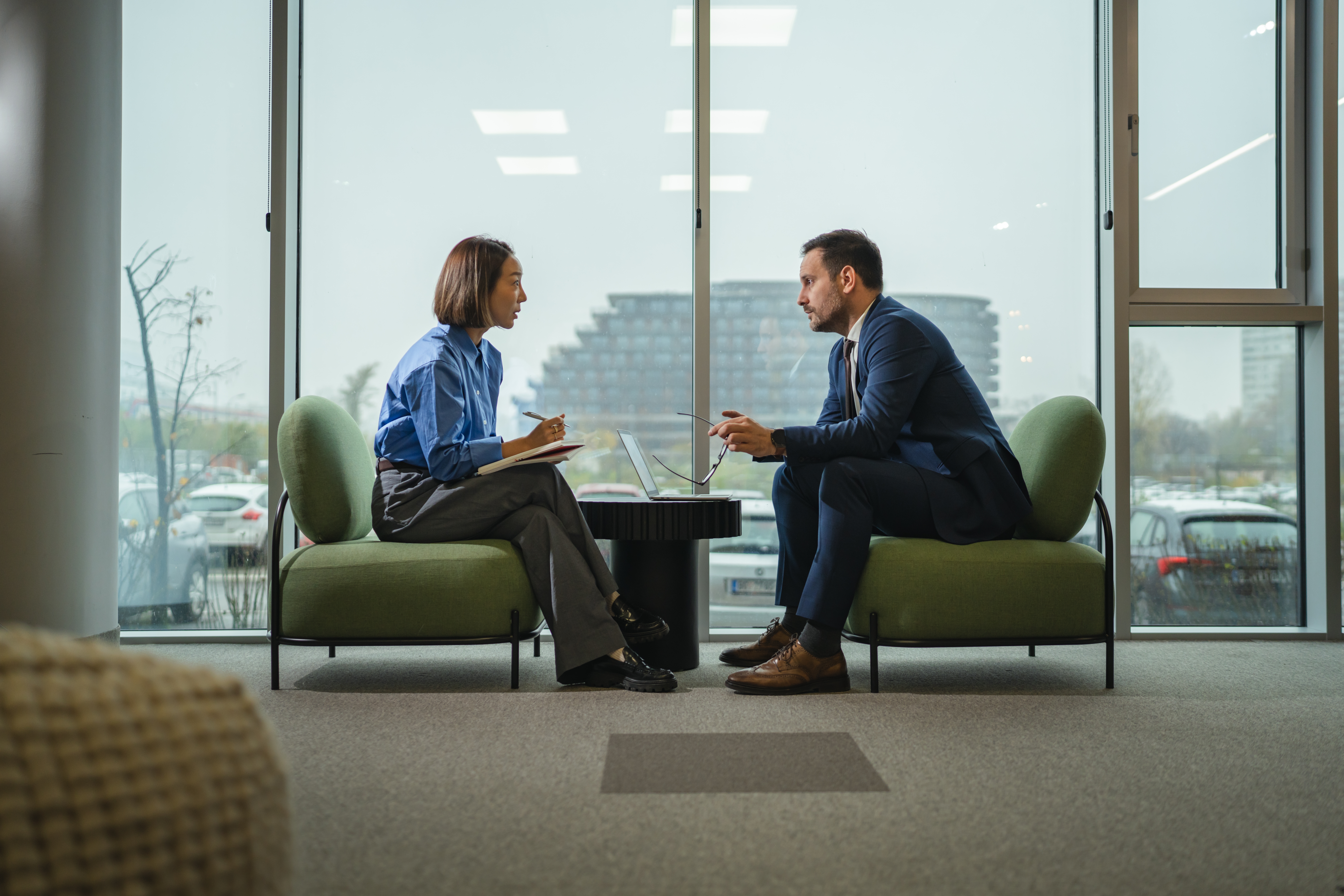 Two diverse professionals in a modern office engaged in a serious interview or meeting