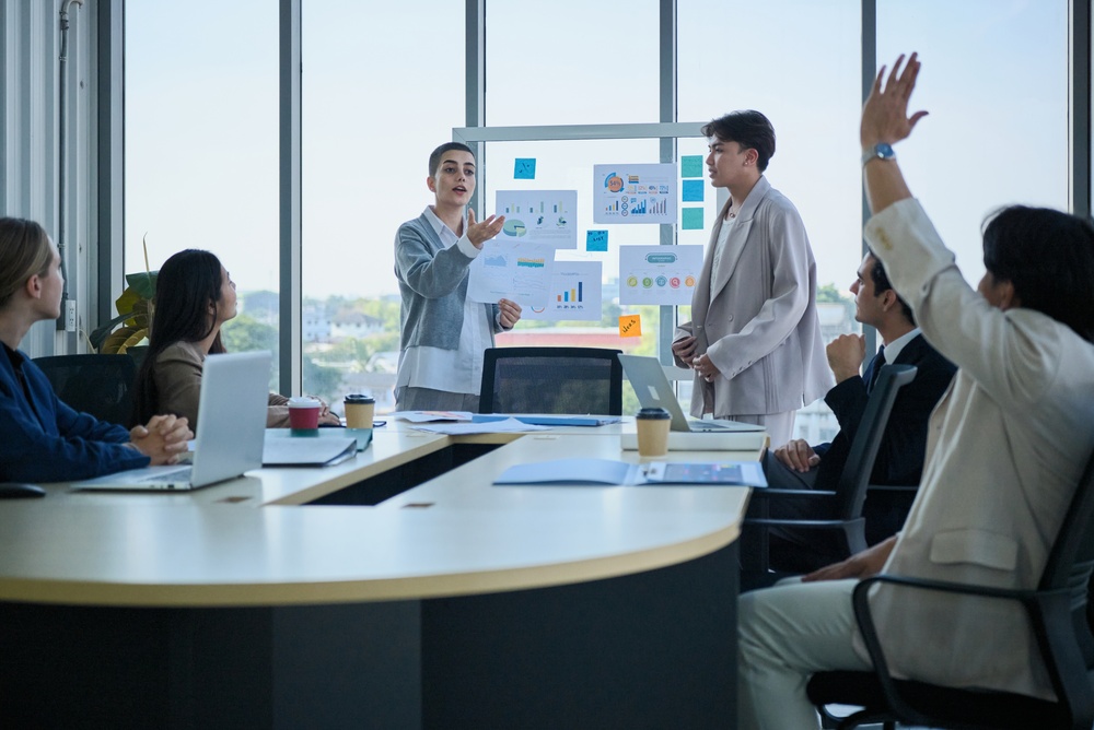 Young company coworkers explain finance and marketing investment analysis, team questions, ask, discuss, and brainstorm with multiracial partners in meeting and business strategy report presentations.