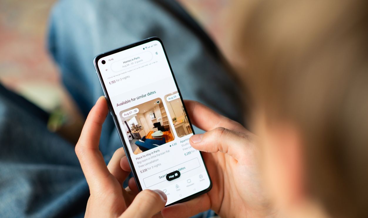 Kyiv, Ukraine - July 28, 2025: Person browsing Airbnb app on smartphone, searching for apartments and booking accommodations for travel or vacation.