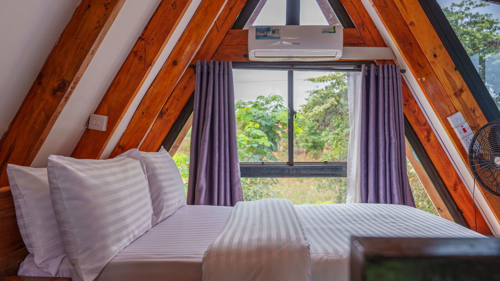 A-frame cabin bedroom with wood accents and forest view, perfect for a nature retreat.