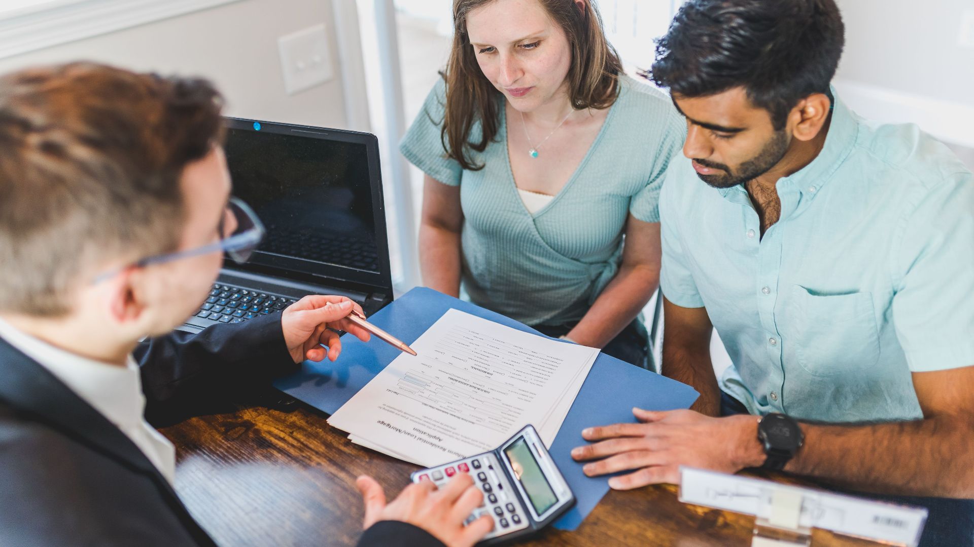 Young couple meeting with real estate agent to discuss property purchase.
