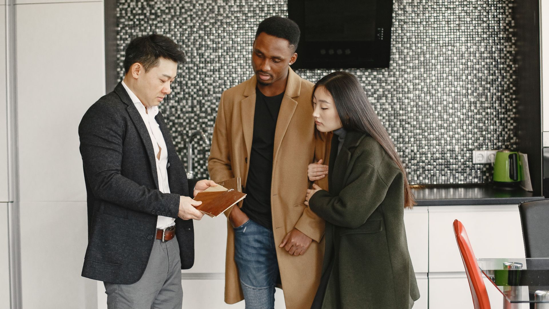 A business meeting in a contemporary kitchen showing diverse professionals discussing strategic options.