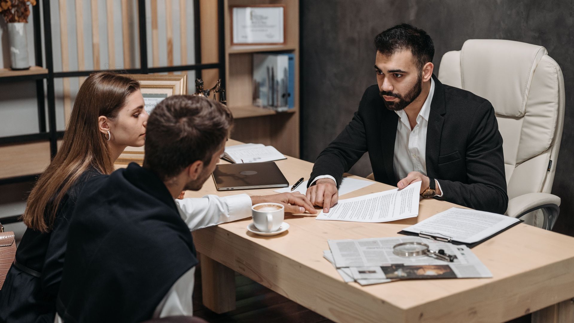 Lawyer discussing legal documents with clients at office desk.