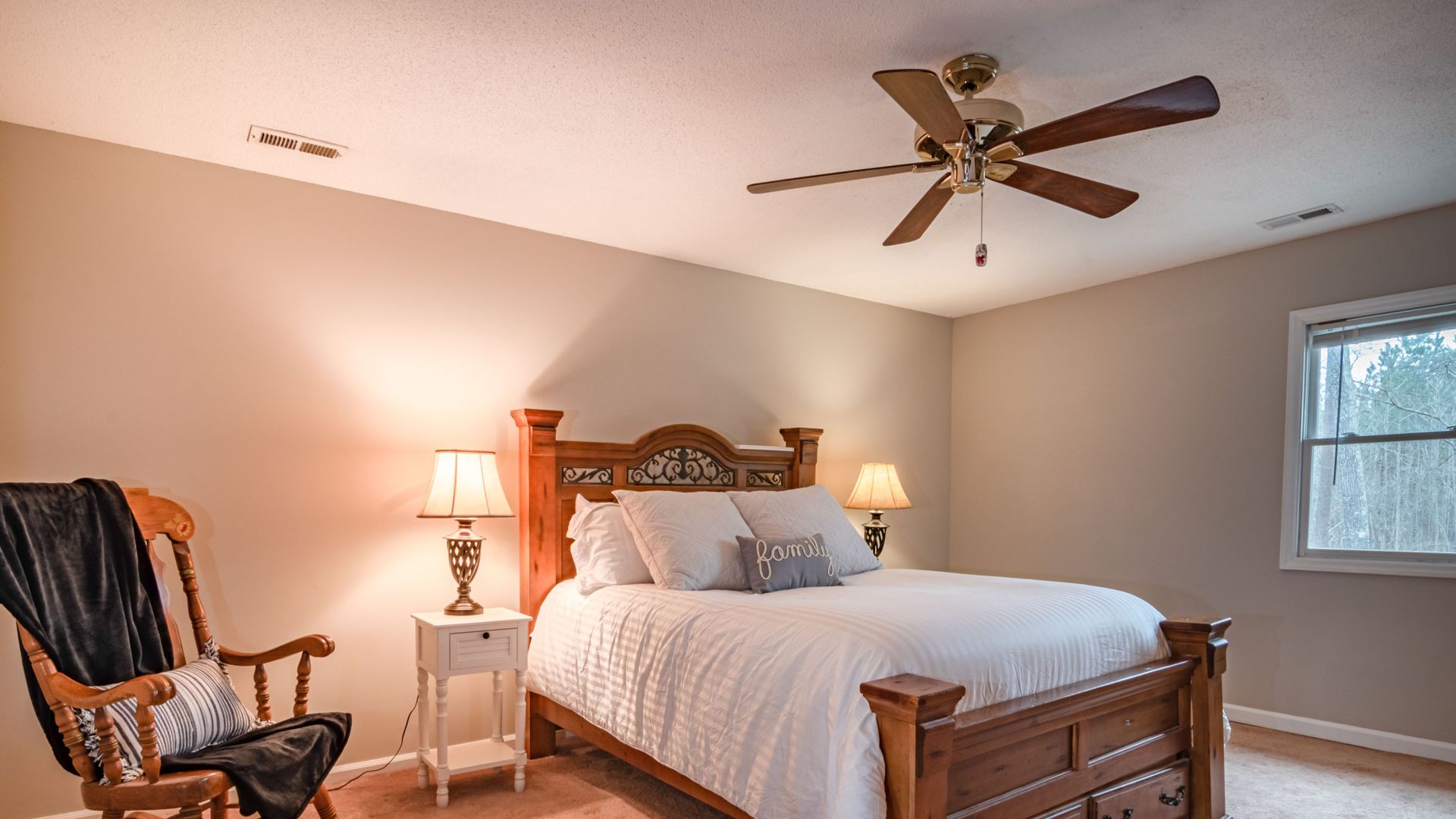 Warm and inviting bedroom featuring a wooden bed, ceiling fan, and cozy decor.
